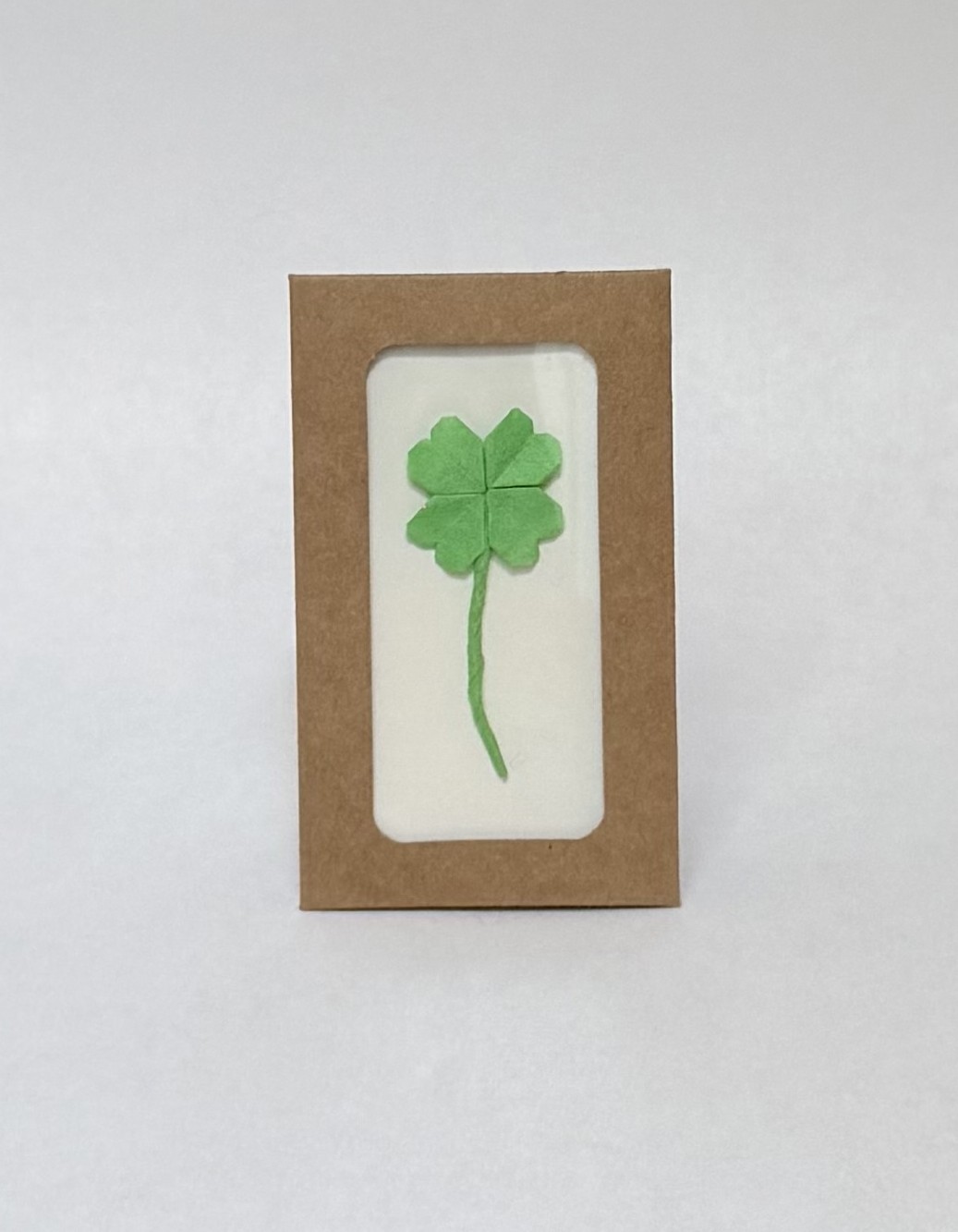 An image showing a green shamrock displayed in a frame, folded from paper.